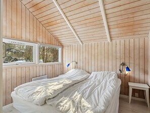 A bedroom with wooden walls, a bed, a window, and two wall-mounted lamps. - "Elenor" - 1.3km from the sea by Interhome (Græsted)
