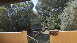Een terras buiten met uitzicht op een tuin, een stenen muur en een metalen poort.