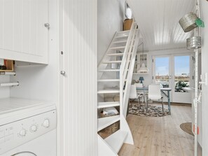Et moderne køkken med hvide skabe, indbygget ovn og spiseplads med bord og stole.