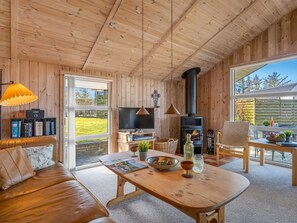 Acogedor interior de cabaña con sofá, mesa de comedor de madera, televisor y chimenea.