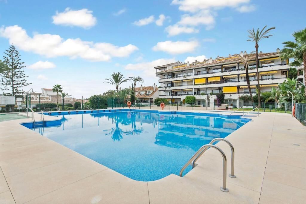 A swimming pool with a clear blue water surface, surrounded by a tiled deck.