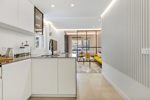 A modern kitchen with a central island, a dining area with a yellow sofa, and a view through a window. - Golden Mile Lux Sea View Suite & Balcony (Marbella)