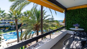A balcony with a view of a pool, palm trees, and a green wall. - Golden Mile Lux Sea View Suite & Balcony (Marbella)