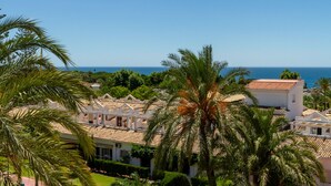 A coastal residential area with white buildings, palm trees, and a clear view of the sea. - Golden Mile Lux Sea View Suite & Balcony (Marbella)