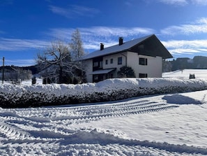 Et toetagers hus med et sneklædt tag og en klar, blå himmel.