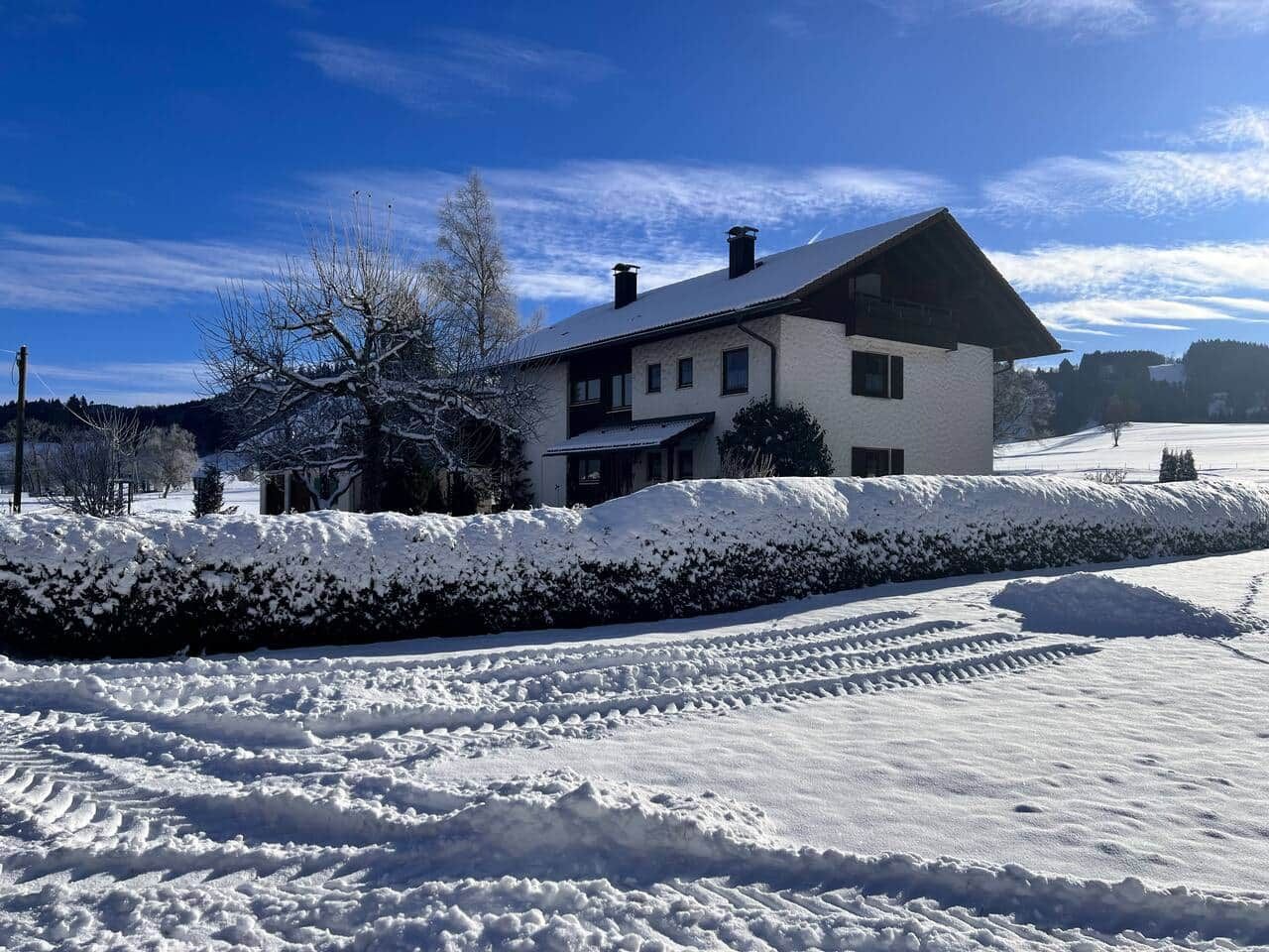 A two-story house with a snow-covered roof and a clear blue sky.
