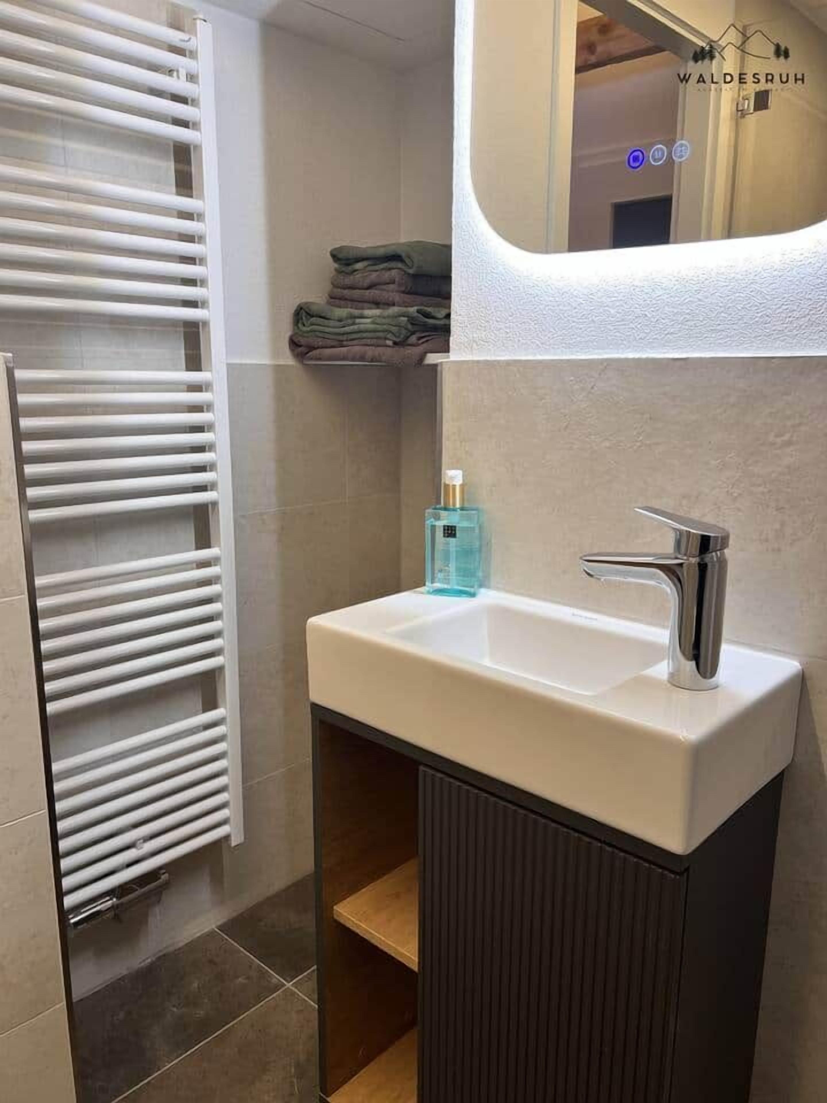 Une salle de bain avec un lavabo blanc, un miroir et un porte-serviettes.