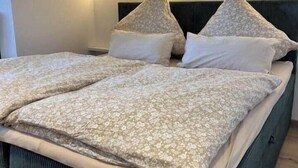 Un lit avec une tête de lit, des oreillers et une couverture.