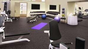 Ett gym med träningsredskap, en bänk, hantlar och en yogamatta.