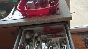 A kitchen with a dish rack holding various utensils and a drawer with neatly organized kitchen tools. - Basildon Holiday Home Essex UK (Basildon)