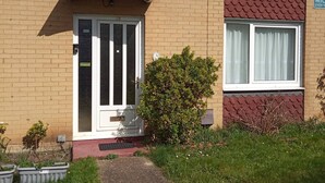 A two-story residential building with a brick facade, a front door with a small porch, and a pathway leading to the entrance. - Basildon Holiday Home Essex UK (Basildon)