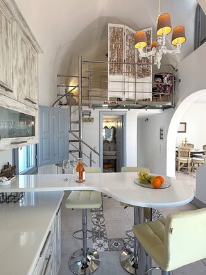 Eine moderne Küche mit einer zentralen Kochinsel, Barhocker, einem Chandelier und einer Treppe zu einer oberen Ebene.