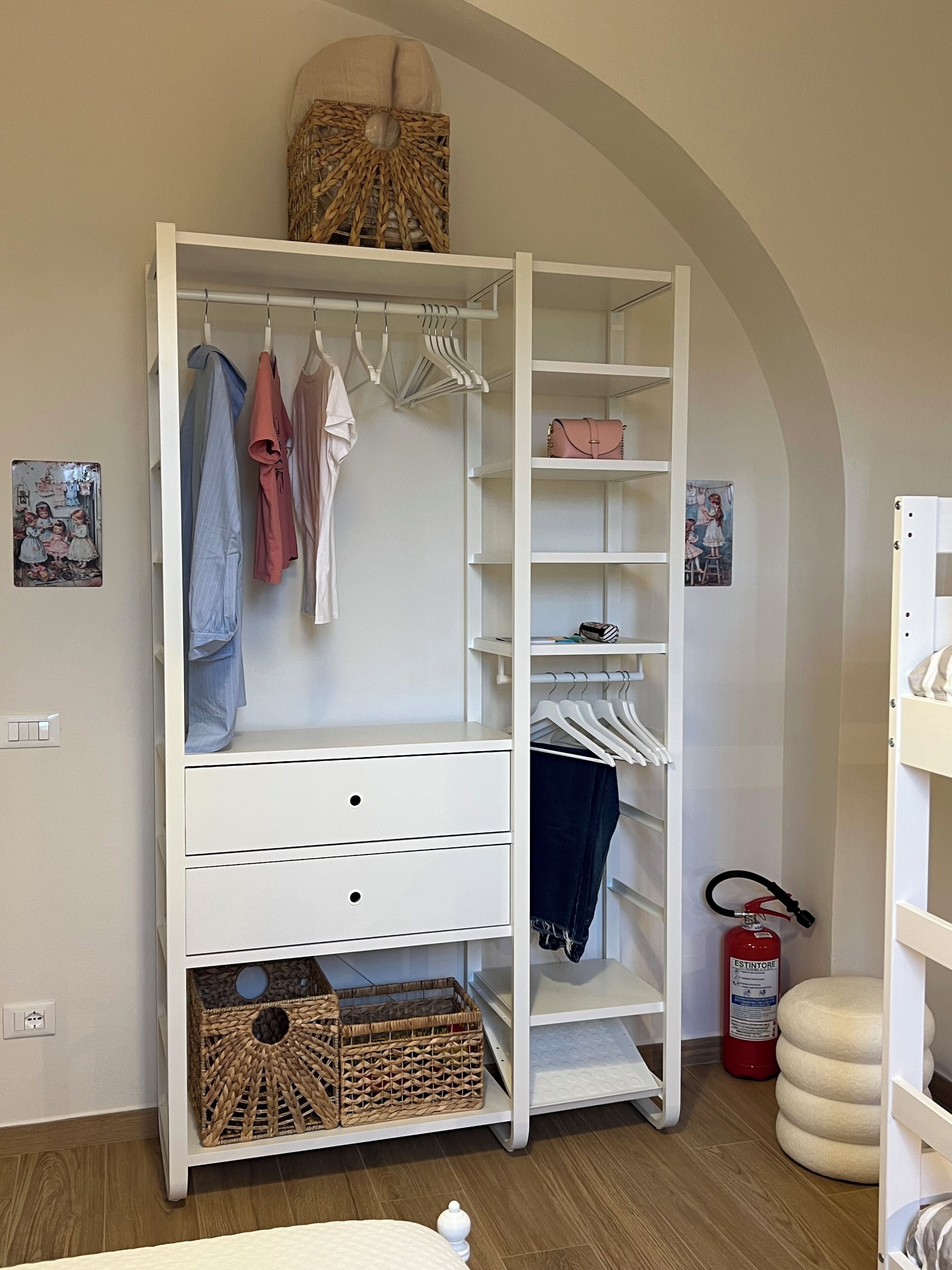A white walk-in closet with open shelves, hanging space, and drawers.