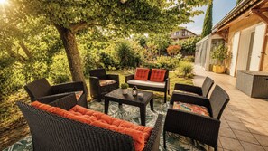 Une terrasse extérieure avec des meubles en osier, une table et un banc.