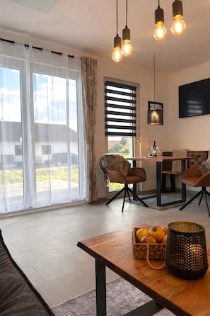 A modern living room with a wooden coffee table, a sofa, and a dining area with a table and chairs.