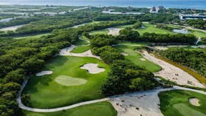 An aerial view of a golf course with multiple holes, sand bunkers, and a surrounding forested area. - Grand Mayan Vidanta 2BR Luxury Suite + Pools & Beach (Playa Paraiso)
