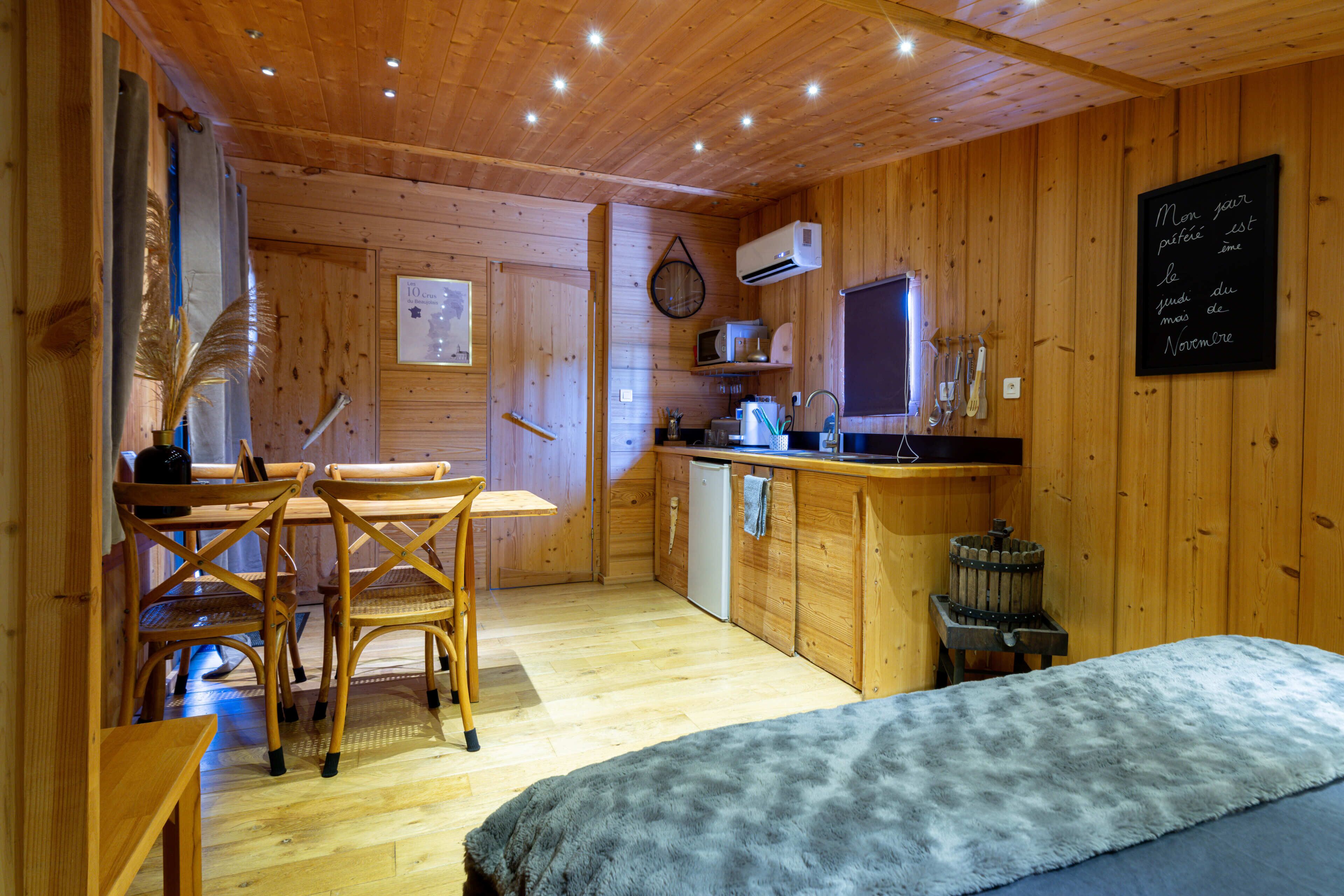 Un interior de madera con comedor, cocina y cama.