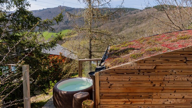 A wooden cabin with a hot tub and a view of a valley. - Small cottage in the heart of Beaujolais (Rivolet)