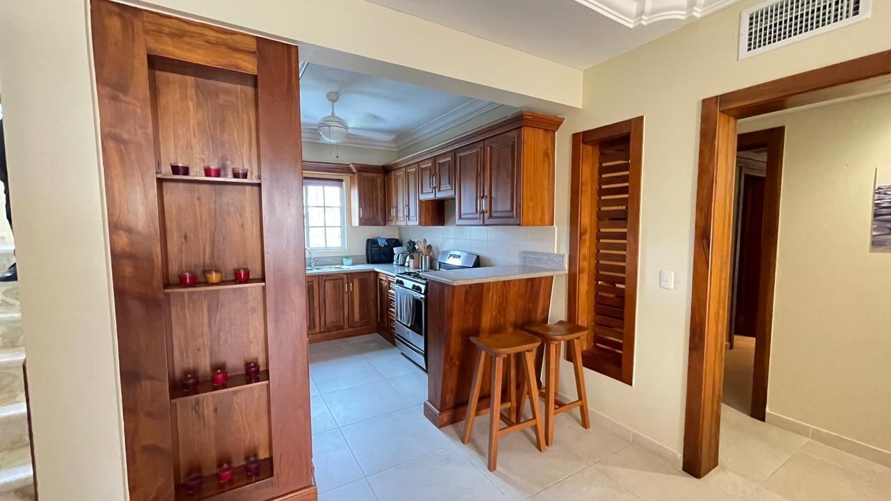 Una cocina con armarios de madera, una encimera y dos taburetes.
