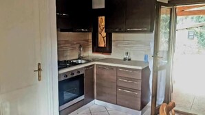 Een keuken met donkere kastjes, een fornuis, een oven en een raam.
