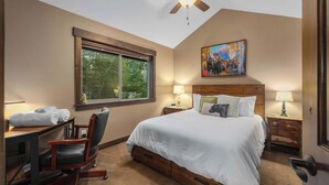 A bedroom with a bed, desk, chair, nightstands, lamps, and a ceiling fan. - Chickadee Cabin - Boutique Stay close to Downtown (Whitefish)