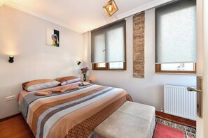 A bedroom with a bed, a bench, a wall-mounted light, a radiator, and a window with a blind. - Taksim Private Terrace Near Museum of Innocence (Istanbul)