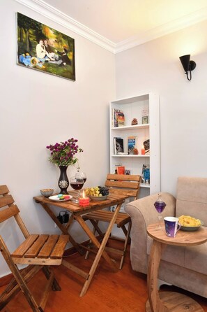 A cozy living room with a wooden table, chairs, a bookshelf, and a painting on the wall. - Taksim Private Terrace Near Museum of Innocence (Istanbul)