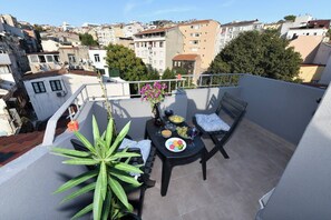 A balcony with a table set for two, a potted plant, and a view of the cityscape. - Taksim Private Terrace Near Museum of Innocence (Istanbul)