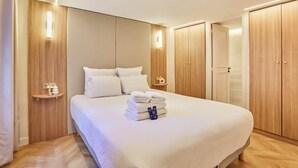Ein Hotelzimmer mit einem großen Bett, einem Holzschrank, Nachttischen und einem Beistelltisch.