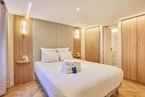 A hotel room with a large bed, wooden wardrobe, bedside tables, and a nightstand. - New Apartment in the Heart of Paris 4 People (Paris)