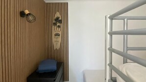 A compact room with a bunk bed, a small desk with a chair, and a wall-mounted surfboard decoration. - Duplex T2 first line on the beach with parking Palavas/Carnon (Palavas-les-Flots)