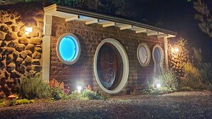 A stone building with circular windows and a stone wall. - Cypress County - Hobbit Themed Lodging (Condor)