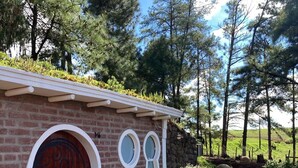 A rustic building with a brick facade, a wooden door with a circular design, and a stone wall. - Cypress County - Hobbit Themed Lodging (Condor)