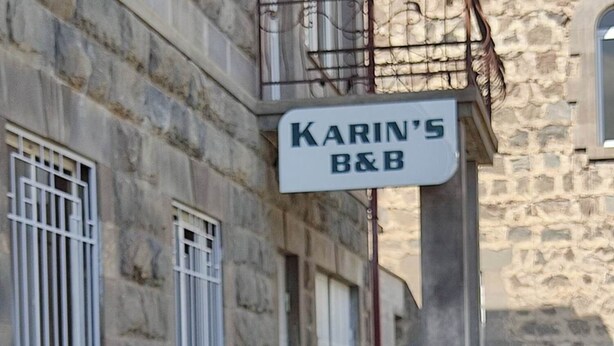 A stone building with a sign reading 'KARIN'S B&B' and a garden with various plants and flowers. - Karin's B&B (Sisian)