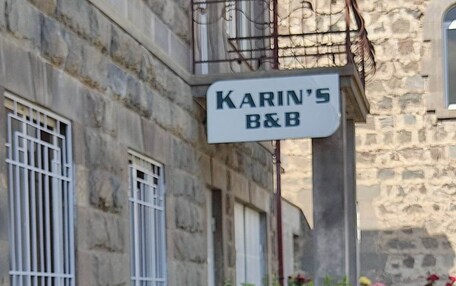 A stone building with a sign reading 'KARIN'S B&B' and a garden with various plants and flowers.