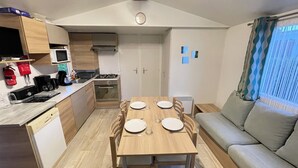 Une cuisine compacte comprenant un coin repas, un canapé et une fenêtre avec des rideaux.