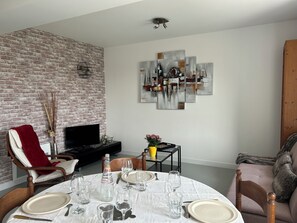 Een eetruimte met een bakstenen muur, een flatscreen televisie en abstracte kunst aan de muur.