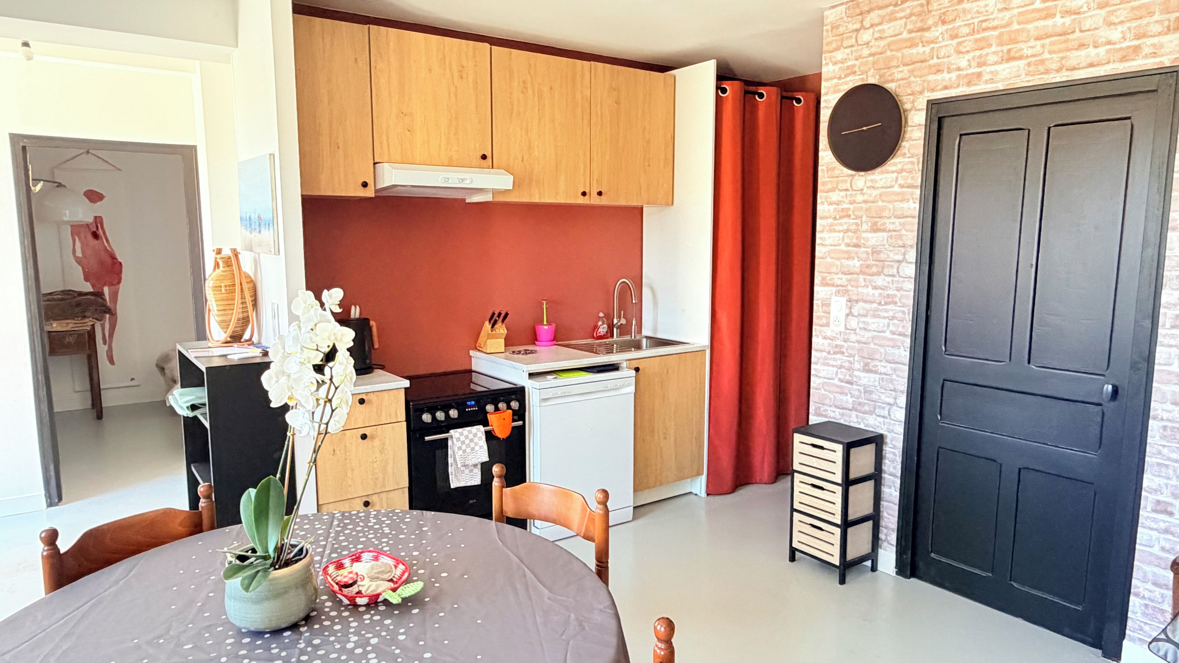 A compact kitchen with wooden cabinets, a white stove, and a red brick wall.