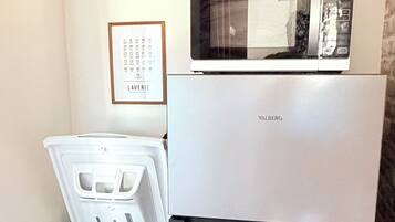 Una cocina compacta con un refrigerador blanco, un microondas y un lavavajillas.