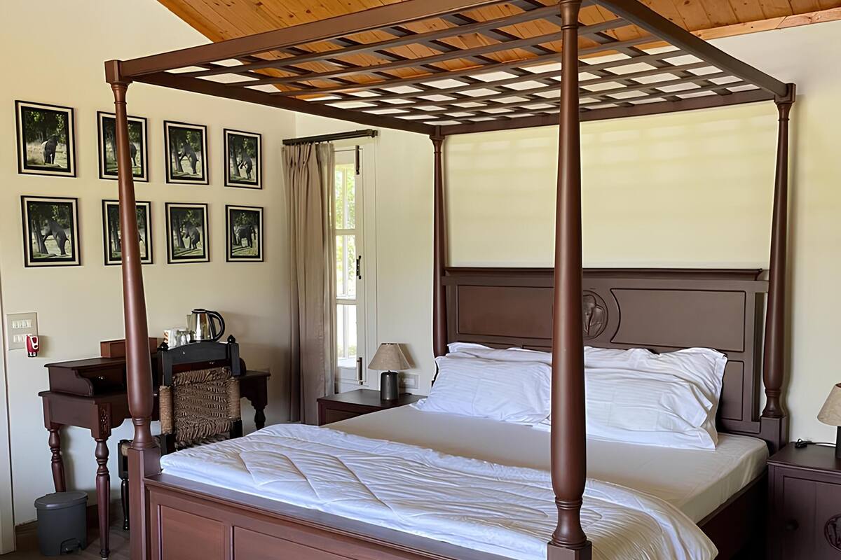 Un lit à baldaquin avec une tête de lit en bois, un tapis rouge à motifs et un ventilateur de plafond.