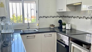 Eine moderne Küche mit weißen Schränken, einer schwarzen Arbeitsplatte, einem Fenster und einer Mikrowelle.