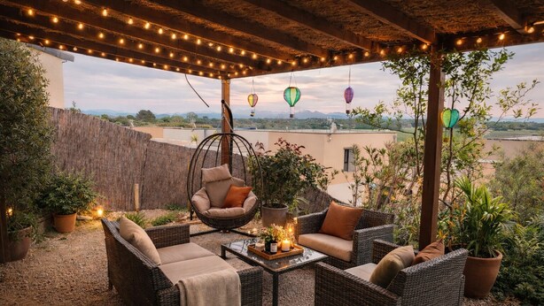 An outdoor patio with wicker furniture, hanging chairs, and string lights. - Family home with garden, trampoline and ideal location (Piolenc)