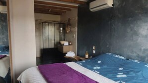 A bedroom with a bed, a nightstand, a mirror, and a bathroom visible in the background. - Family home with garden, trampoline and ideal location (Piolenc)