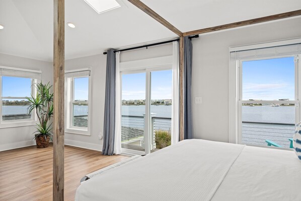 Une chambre avec un grand lit, une vue sur l’eau et un balcon.