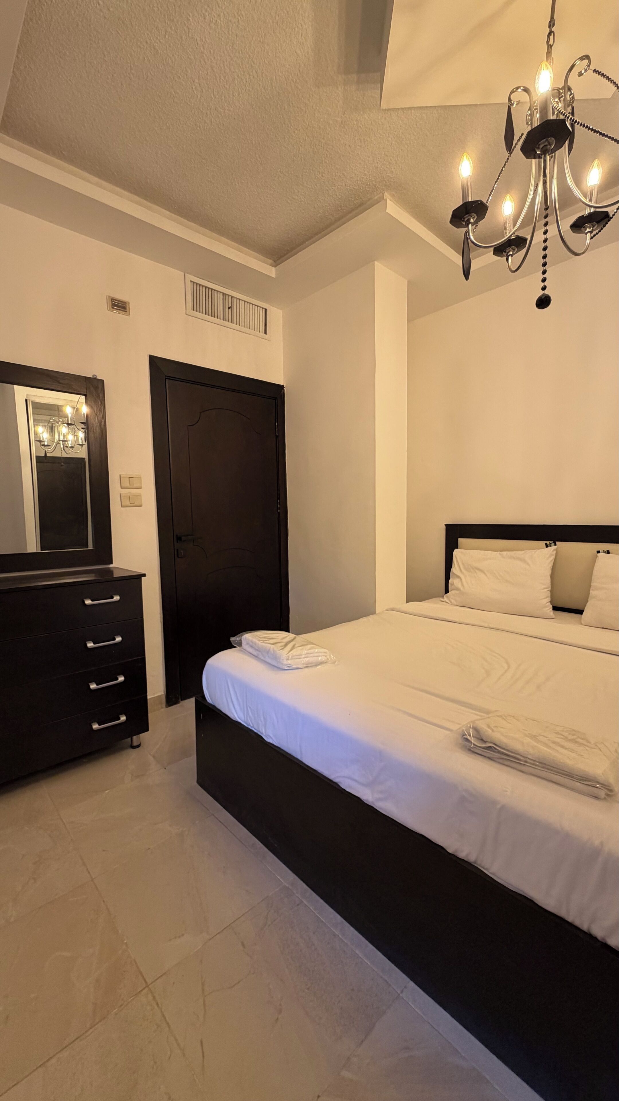 Ein Schlafzimmer mit Bett, Kommode, Spiegel und einer Chandelier.