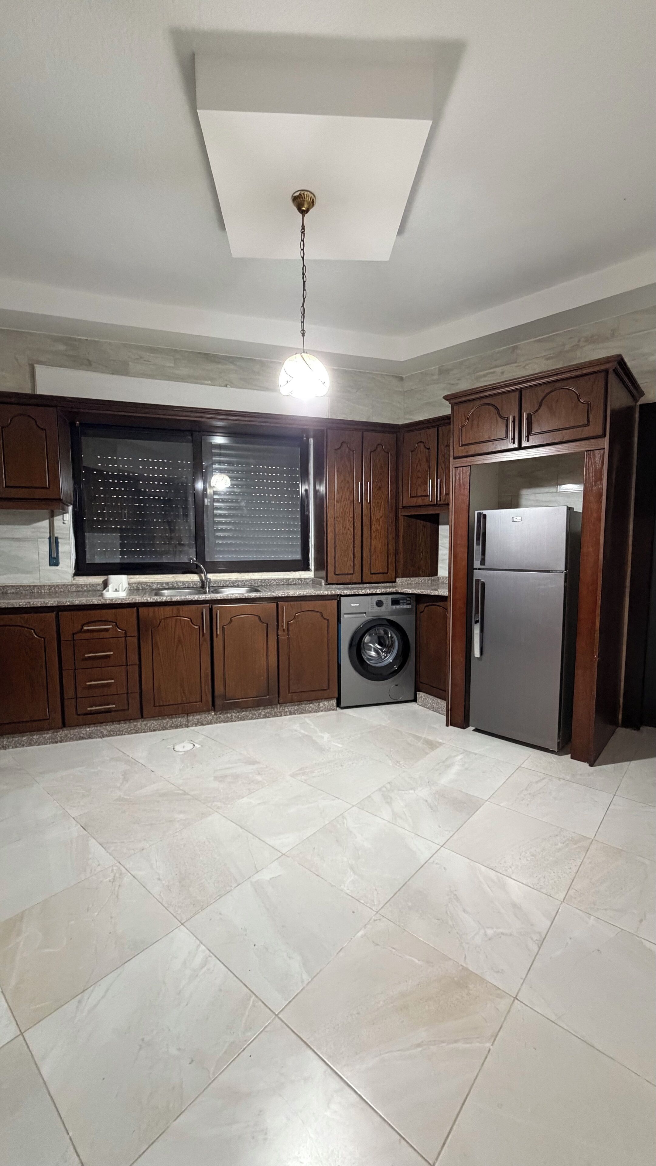 A kitchen with wooden cabinets, a washing machine, and a refrigerator.