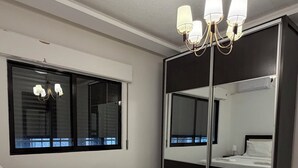 Una habitación de hotel moderna con una cama grande, una lámpara de noche y un espejo con marco negro.