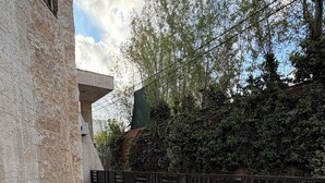 Un patio con suelo de baldosas, baranda de metal y pared de piedra.