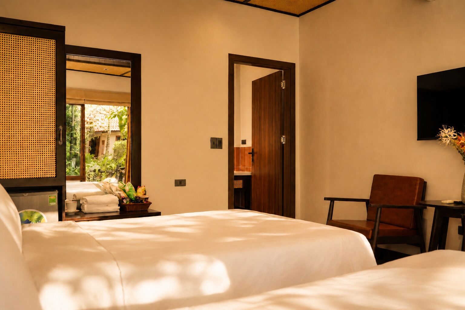 A hotel room with two beds, a desk, a chair, a TV, and a large mirror.