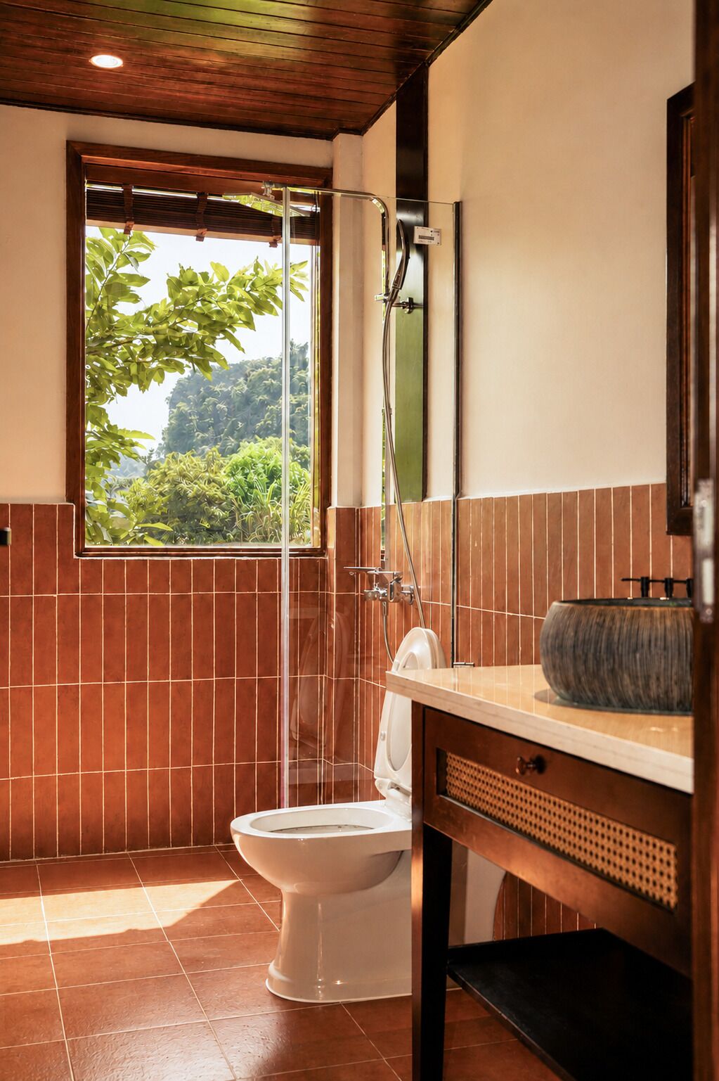A bathroom with a toilet, shower, and a window with a view of greenery.